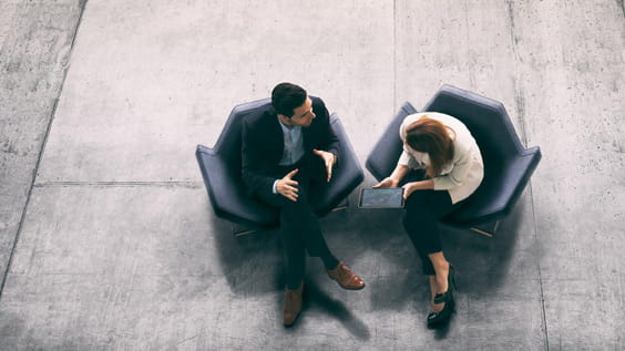 Un par de humanos en sillas sobre un suelo de piedra